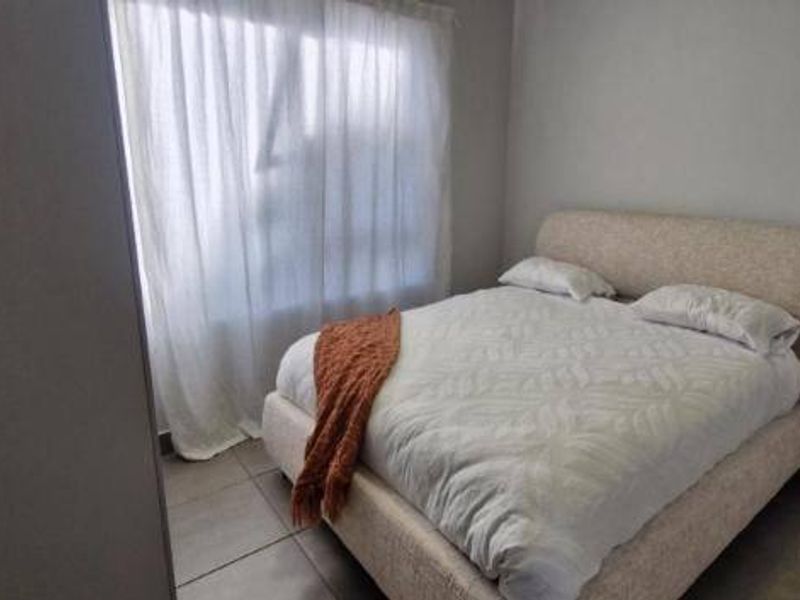 A simple bedroom featuring tiled flooring and a built-in cupboard, providing a functional and neutral space.