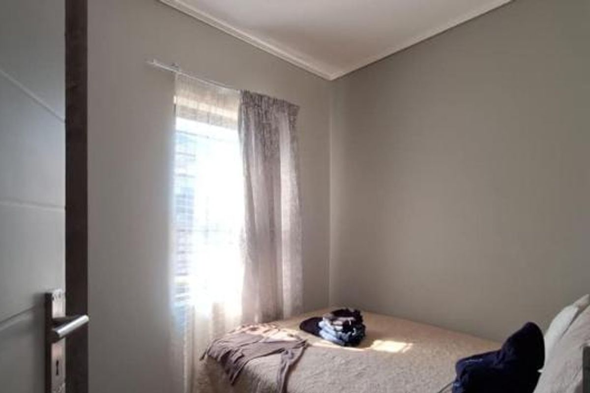 A compact bedroom featuring neutral wall tones and a window with natural light, providing a functional and quiet sleeping space.