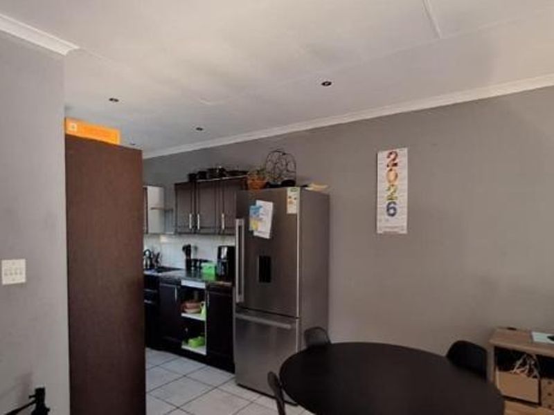 Open plan living area featuring tiled flooring, recessed lighting, and a compact kitchen with built-in cabinetry.
