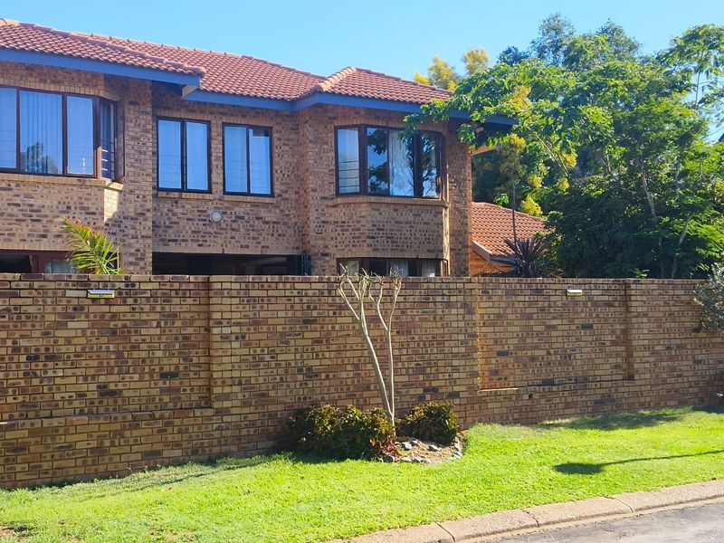 A well-maintained double-story face brick house featuring a tiled roof, bay windows, and a secure perimeter boundary wall.