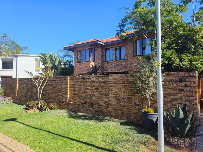 Front view of a double-story face brick house featuring a tiled roof and a secure perimeter boundary wall.