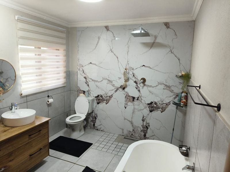 Modern bathroom featuring a freestanding bathtub, walk-in shower with marble-look wall tiles, vessel sink vanity, and contemporary fixtures.