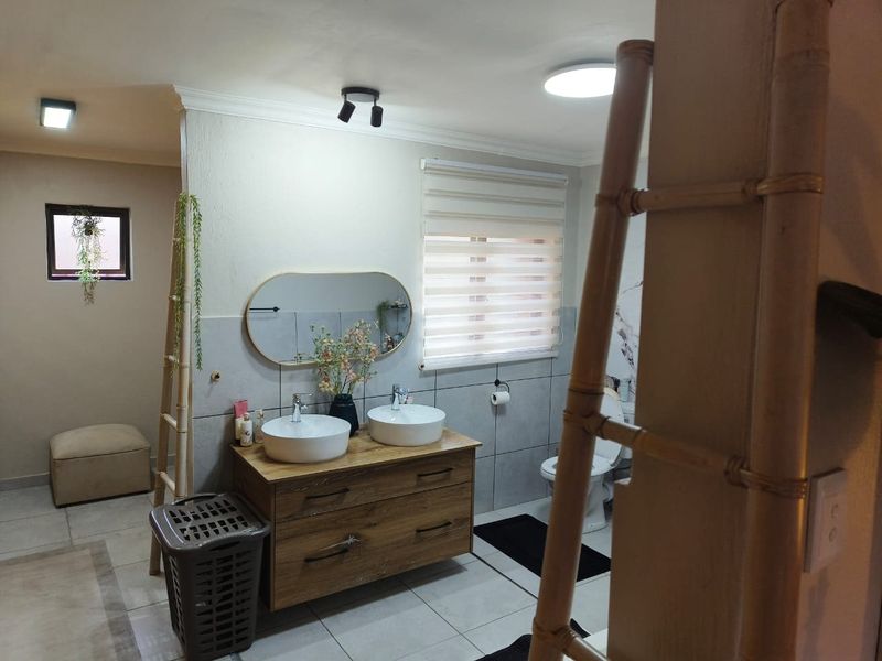 Modern bathroom featuring a double vanity with vessel sinks, tiled walls, and contemporary lighting fixtures.