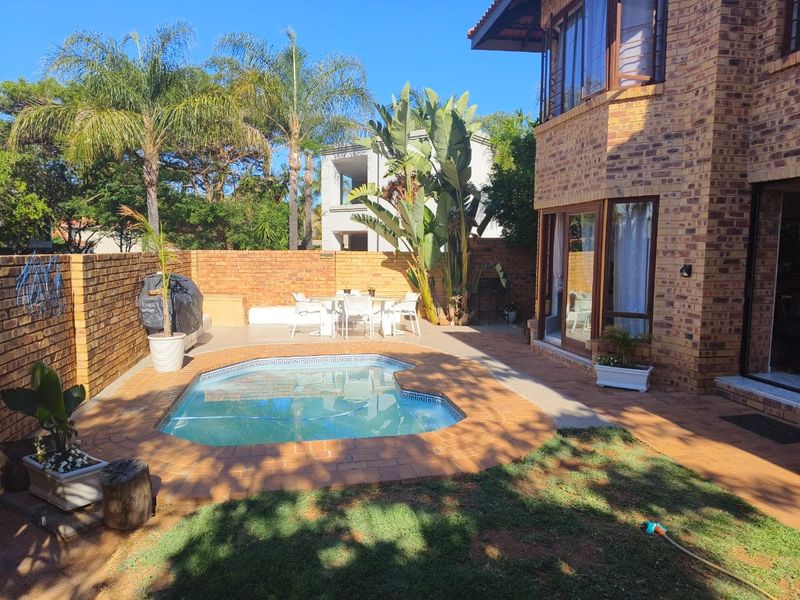 A private outdoor pool area featuring a paved patio, brick boundary walls, and direct access to the main house via sliding glass doors.
