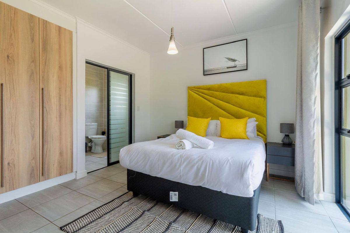 A well-maintained bedroom featuring tiled flooring, a built-in wardrobe, and direct access to an en-suite bathroom.