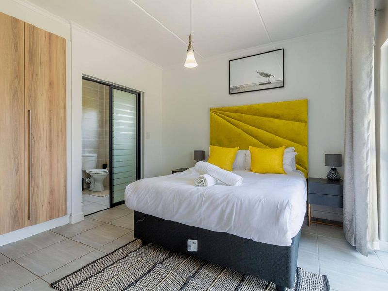 A well-maintained bedroom featuring tiled flooring, a built-in wardrobe, and direct access to an en-suite bathroom.