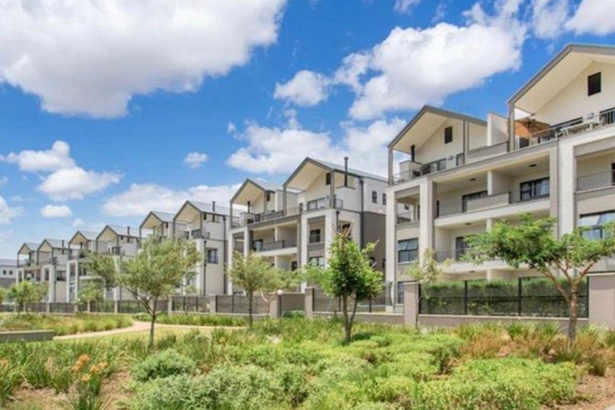 A view of the apartment complex exterior featuring modern architecture, private balconies, and well-maintained landscaped gardens and pathways.