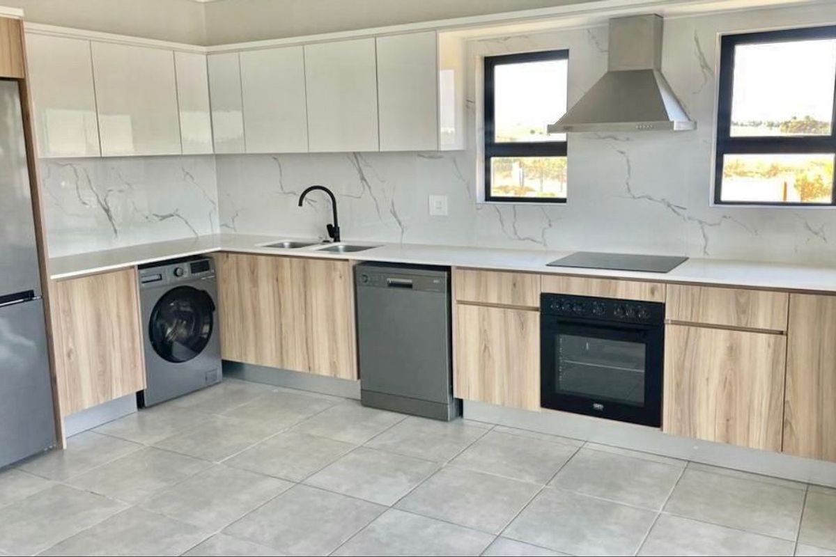 Modern kitchen featuring sleek white and wood-grain cabinetry, marble-look splashback, integrated appliances, and high-quality tiled flooring.