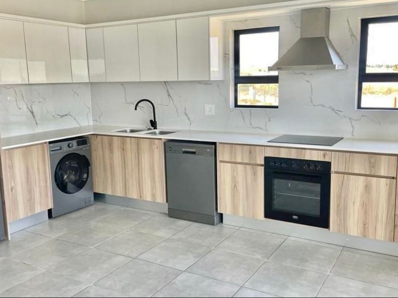 Modern kitchen featuring sleek white and wood-grain cabinetry, marble-look splashback, integrated appliances, and high-quality tiled flooring.