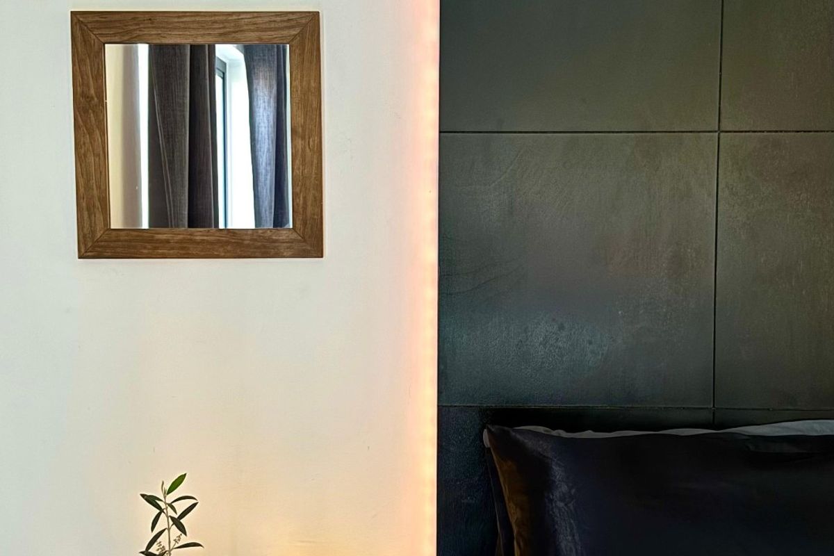 A modern bedroom featuring a sleek, backlit dark feature wall panel behind the bed area.