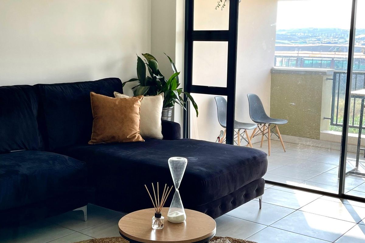 A bright living room featuring tiled flooring and large sliding glass doors that provide access to an outdoor balcony area.