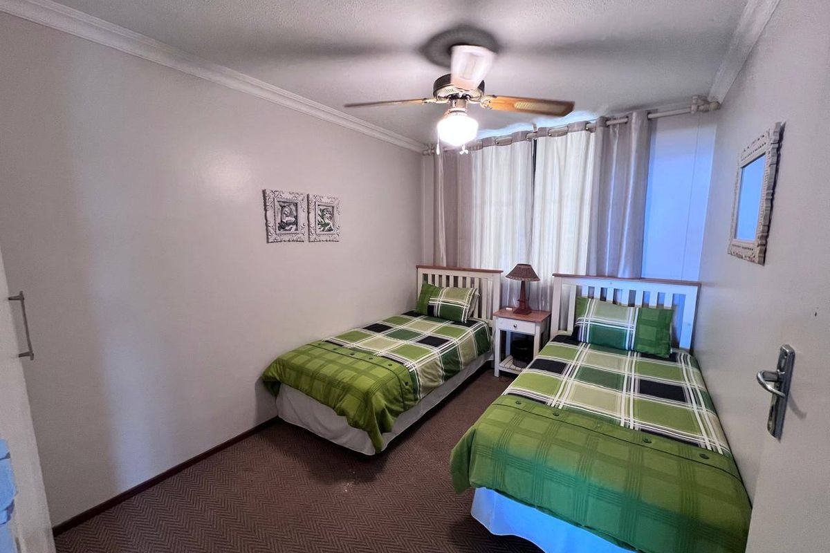 A functional bedroom featuring carpeted flooring, a ceiling fan, and built-in cupboard storage, offering a comfortable and practical living space.