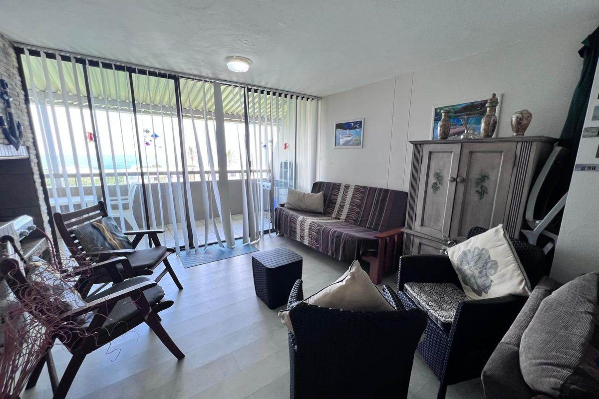 A living room featuring laminate flooring and large sliding glass doors that provide access to an outdoor balcony area.