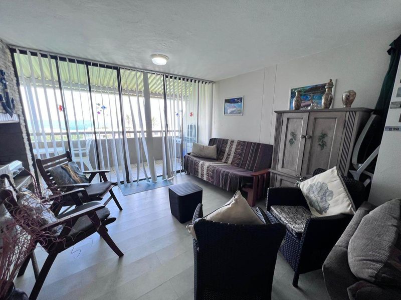 A living room featuring laminate flooring and large sliding glass doors that provide access to an outdoor balcony area.
