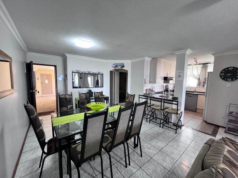 Open-plan dining and kitchen area featuring tiled flooring, coved cornicing, and a functional kitchen layout with a breakfast counter.