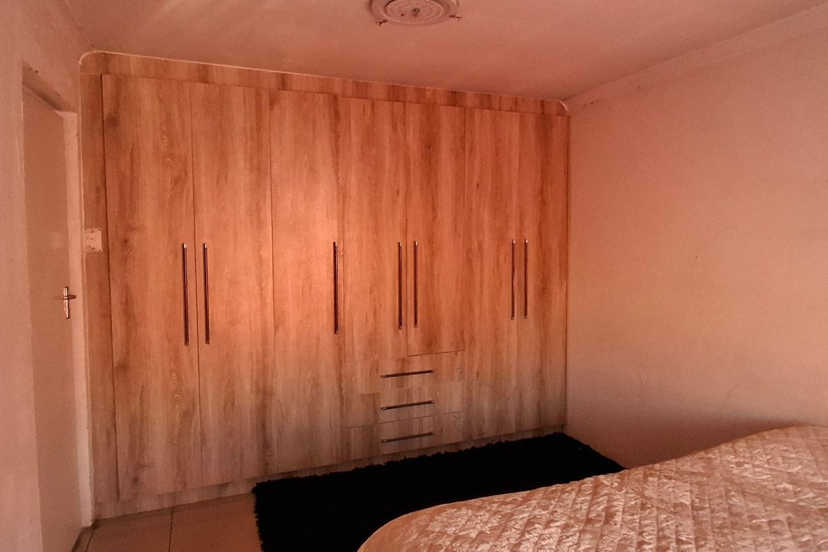 A bedroom featuring extensive built-in wooden cupboards and tiled flooring, providing ample storage space.