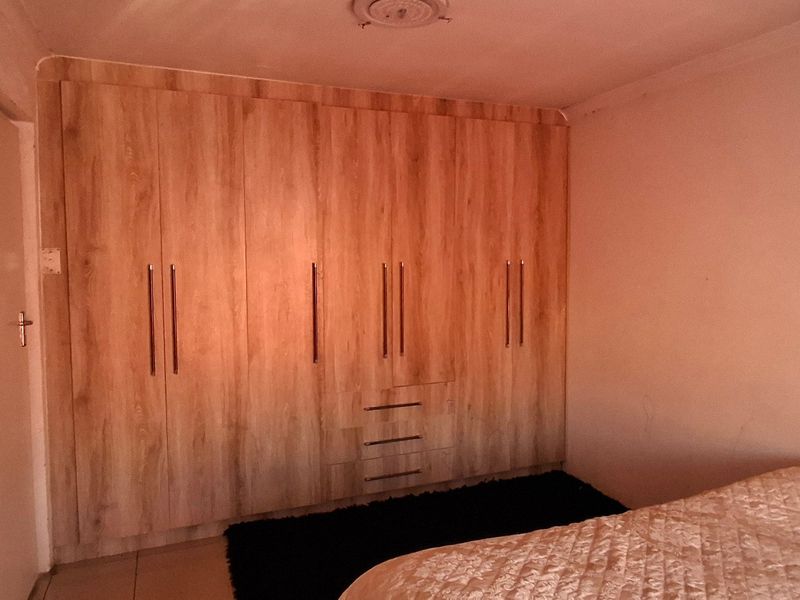 A bedroom featuring extensive built-in wooden cupboards and tiled flooring, providing ample storage space.