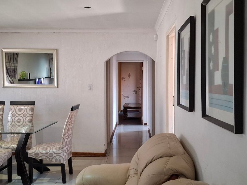 Open plan living and dining area featuring tiled flooring, recessed lighting, and an arched entryway leading to the hallway.