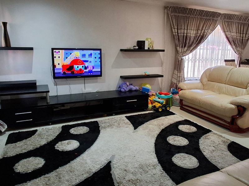 A comfortable living room featuring tiled flooring, recessed ceiling lighting, and a window fitted with a security gate.