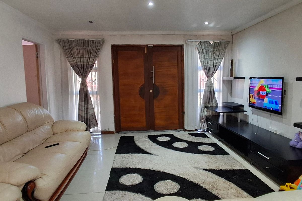 A living room featuring tiled flooring, recessed ceiling lighting, and a prominent double wooden entrance door with flanking windows.