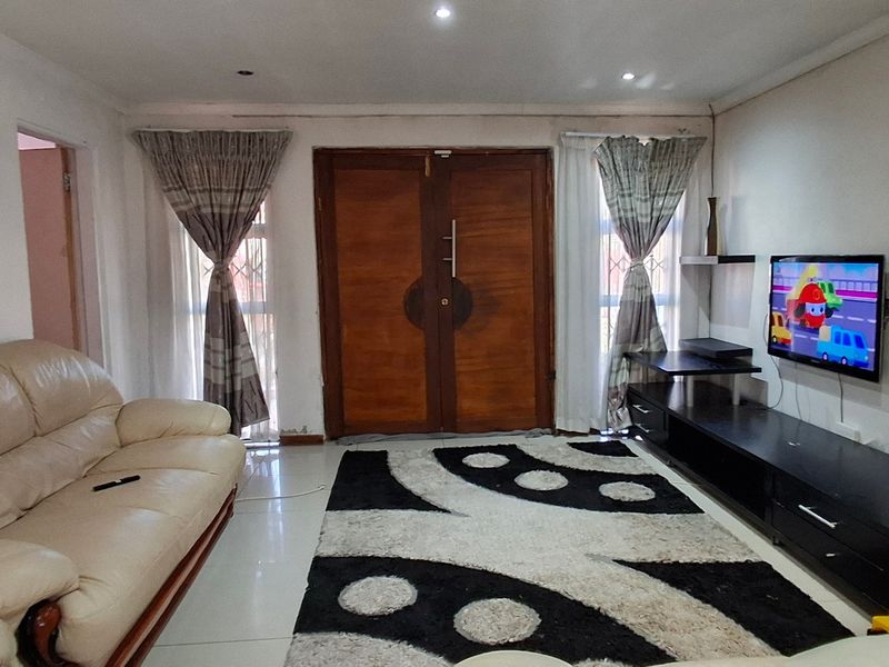 A living room featuring tiled flooring, recessed ceiling lighting, and a prominent double wooden entrance door with flanking windows.