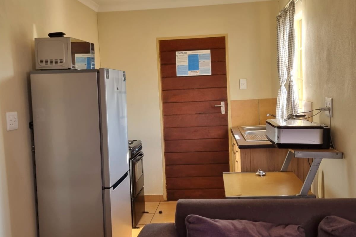 A compact kitchen area featuring tiled flooring, basic cabinetry, and a built-in stove, providing a functional space for meal preparation.