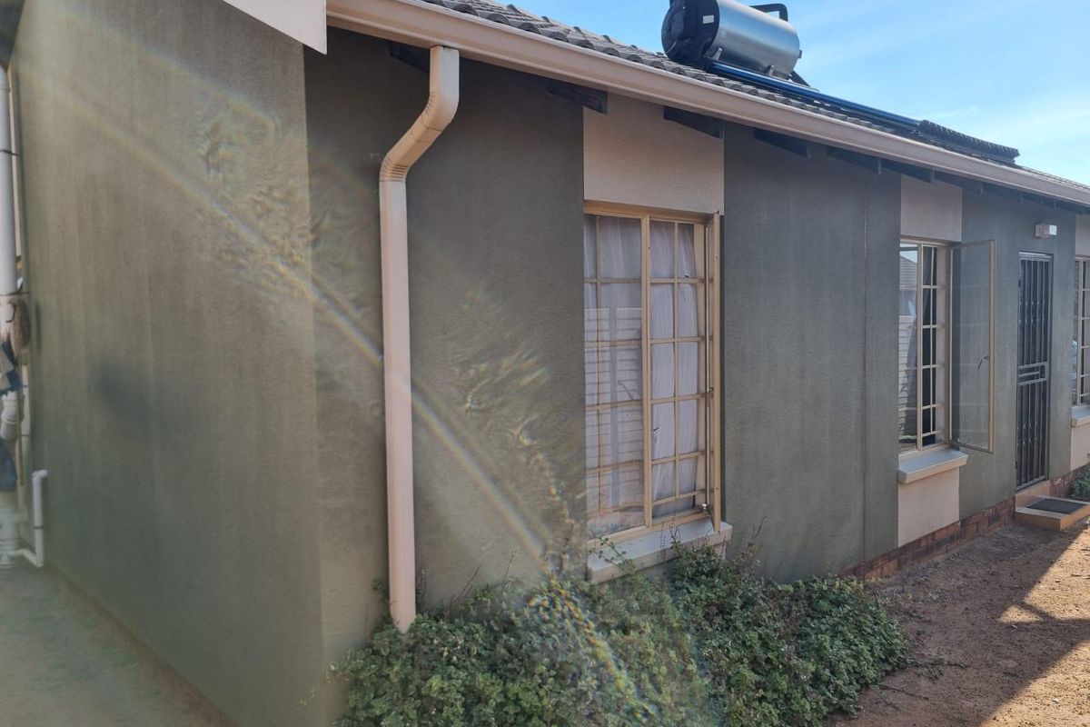 Rear exterior view of the house featuring a solar water heating system, tiled roof, and security features on windows and doors.