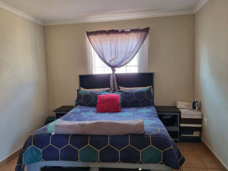 A standard bedroom featuring tiled flooring and neutral wall finishes, providing a functional space with natural light from a central window.