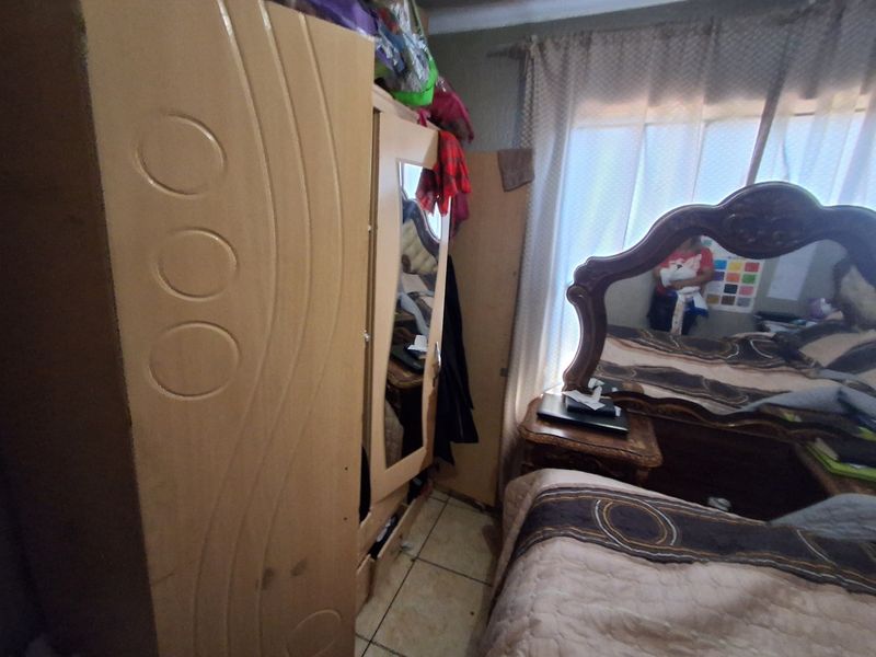 A bedroom featuring tiled flooring and window treatments, currently furnished with bedroom suite cabinetry.