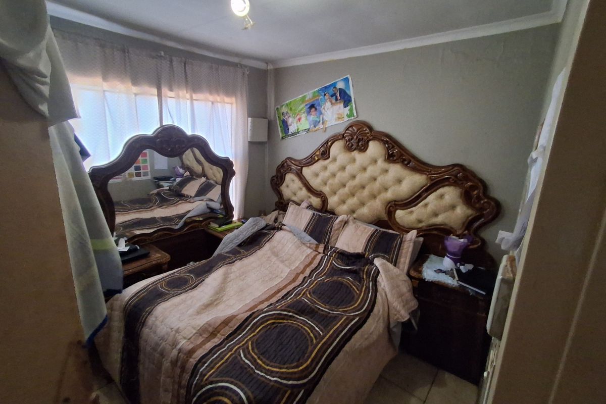 A bedroom featuring tiled flooring and standard lighting, currently requiring cosmetic updates to the wall finishes to improve the overall aesthetic.