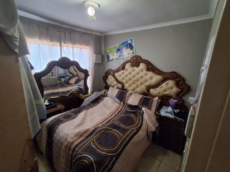 A bedroom featuring tiled flooring and standard lighting, currently requiring cosmetic updates to the wall finishes to improve the overall aesthetic.