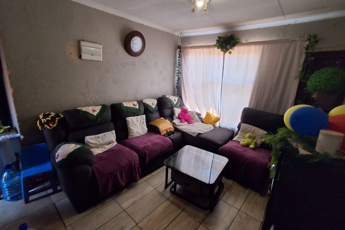 A living room featuring tiled flooring and coving, currently requiring cosmetic updates to the wall surfaces to improve the overall aesthetic.