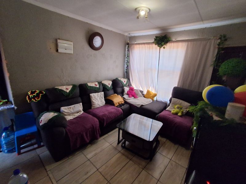 A living room featuring tiled flooring and coving, currently requiring cosmetic updates to the wall surfaces to improve the overall aesthetic.