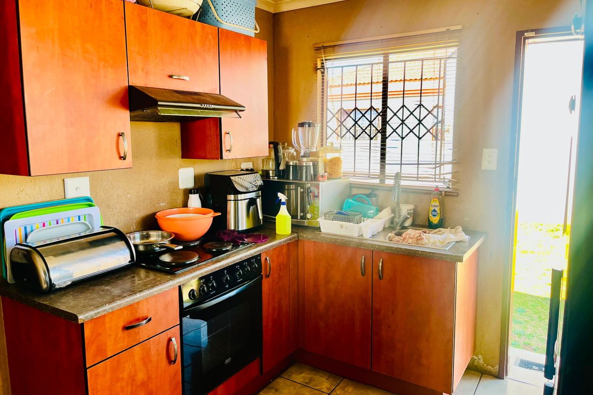 A functional kitchen featuring wood-tone cabinetry, laminate countertops, built-in oven with hob, and direct access to the exterior.