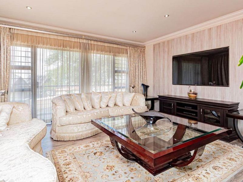 A well-maintained living room featuring laminate flooring, recessed downlighting, and large sliding glass doors that provide ample natural light.