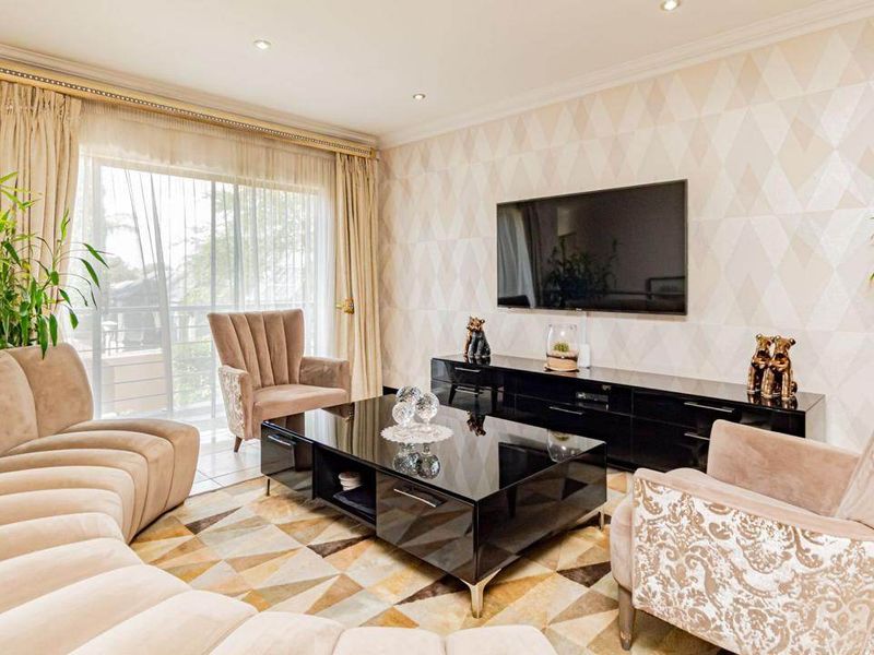 A well-maintained living room featuring tiled flooring, recessed downlights, decorative wallpaper, and a sliding glass door providing natural light.