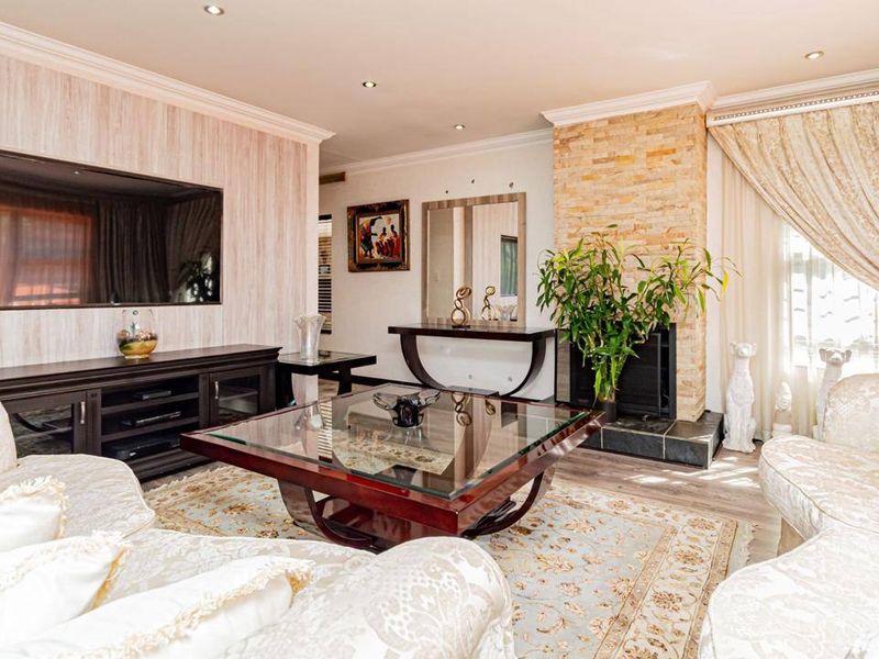 Spacious living room featuring a stone-clad fireplace, recessed downlighting, and elegant crown molding, creating a warm and inviting atmosphere.