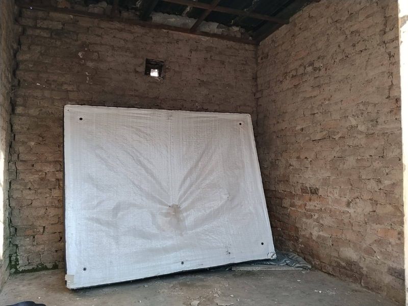 An unfinished utility space featuring exposed brick walls and a concrete floor, requiring significant renovation and finishing work.