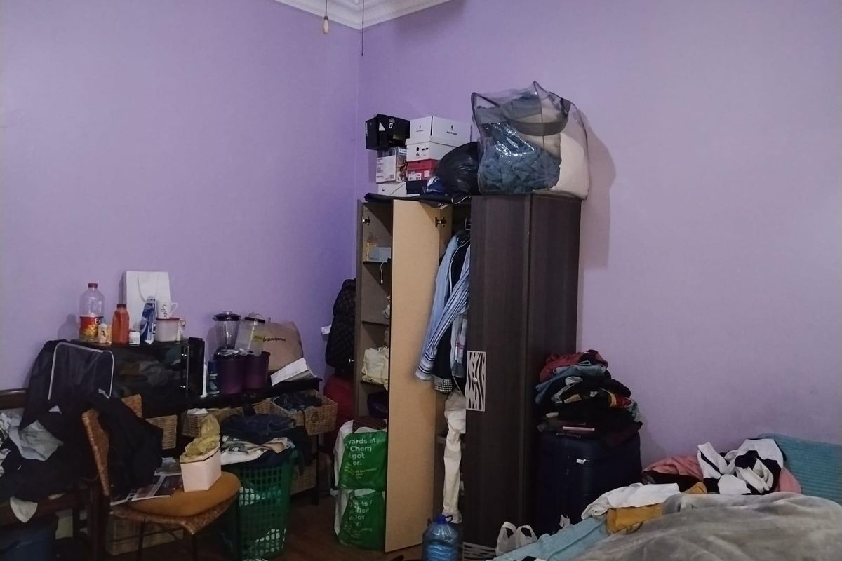 A bedroom featuring decorative ceiling cornicing, currently used as a storage and living space.