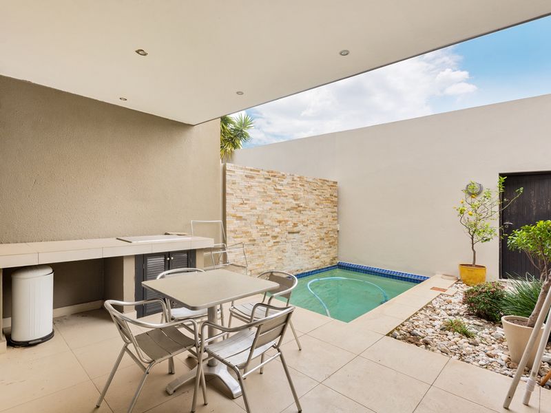 Covered patio area featuring a built-in braai, tiled flooring, and a private plunge pool with a decorative stone feature wall.
