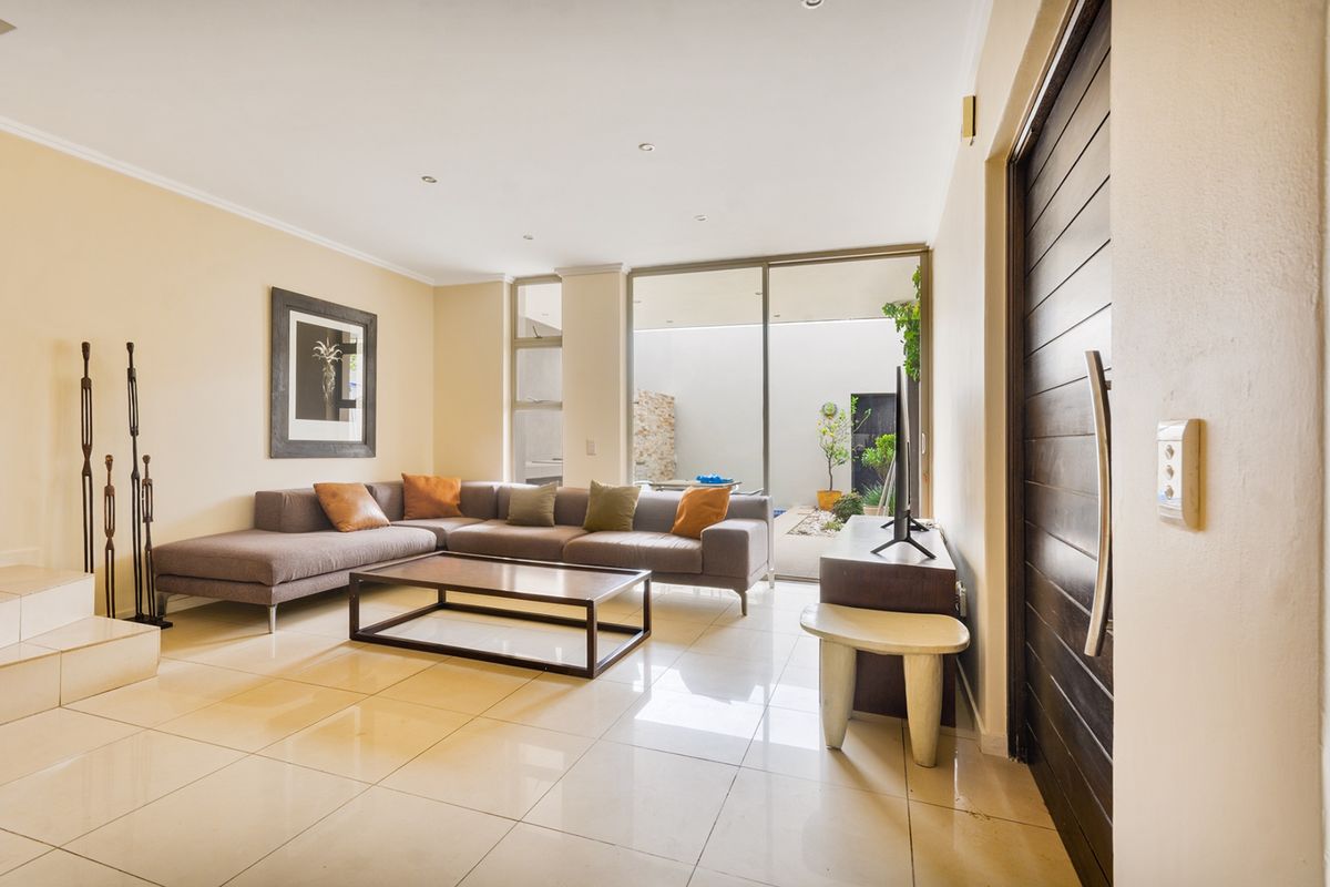 Spacious living room featuring polished tile flooring, recessed lighting, and large sliding glass doors providing seamless access to the outdoor patio area.