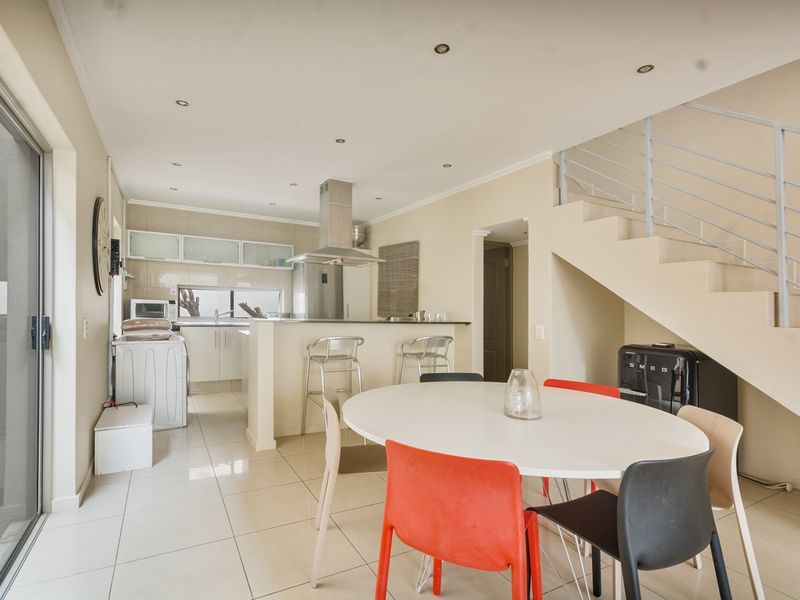 Open-plan kitchen and dining area featuring tiled floors, modern cabinetry, an extractor fan, and direct access to an outdoor patio through sliding glass doors.