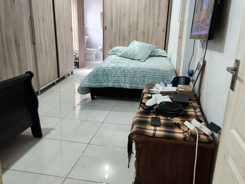 A bedroom featuring built-in wardrobes, tiled flooring, and direct access to an en-suite bathroom.