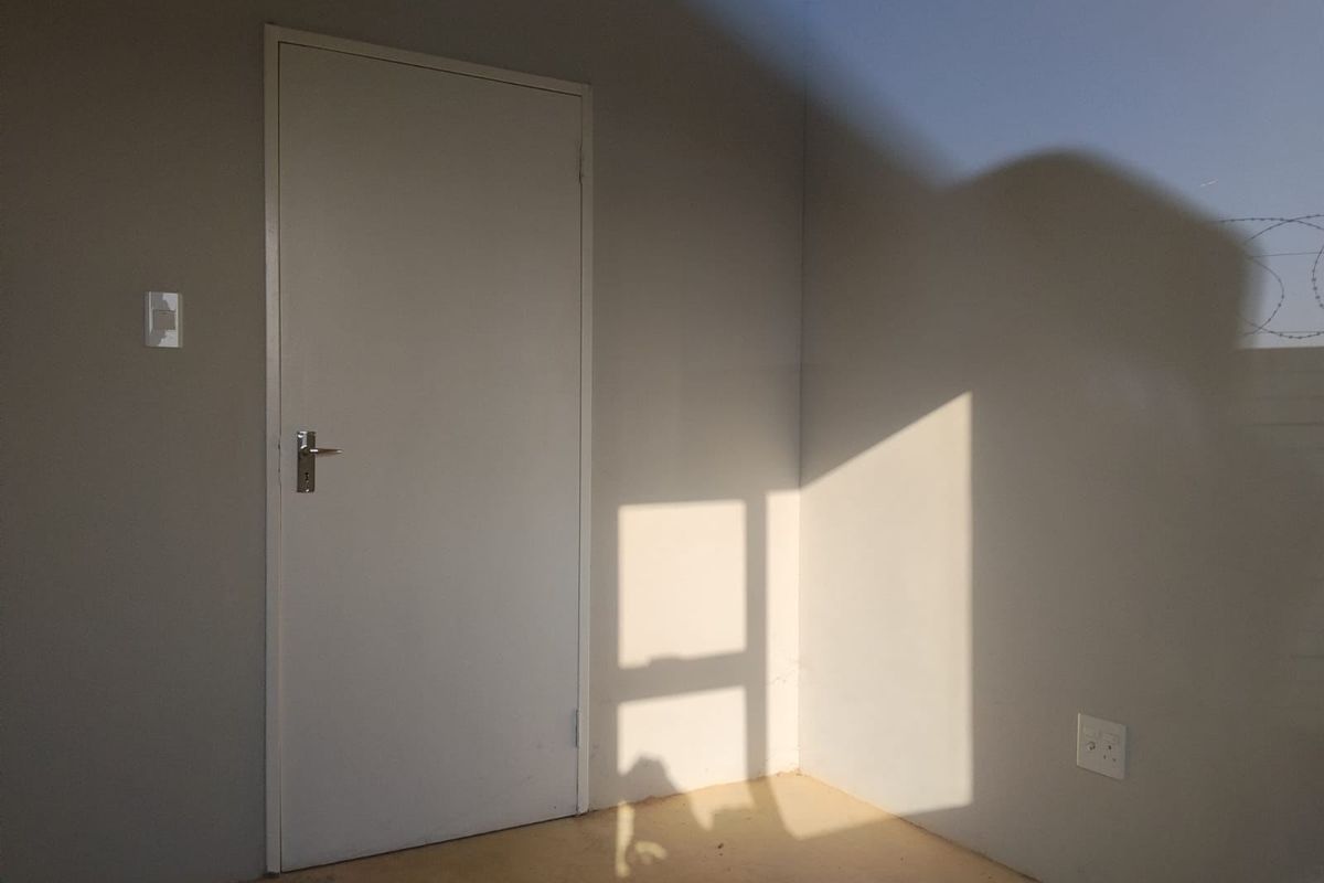An empty bedroom featuring neutral painted walls, a standard internal door, and basic electrical fixtures, ready for personalization.