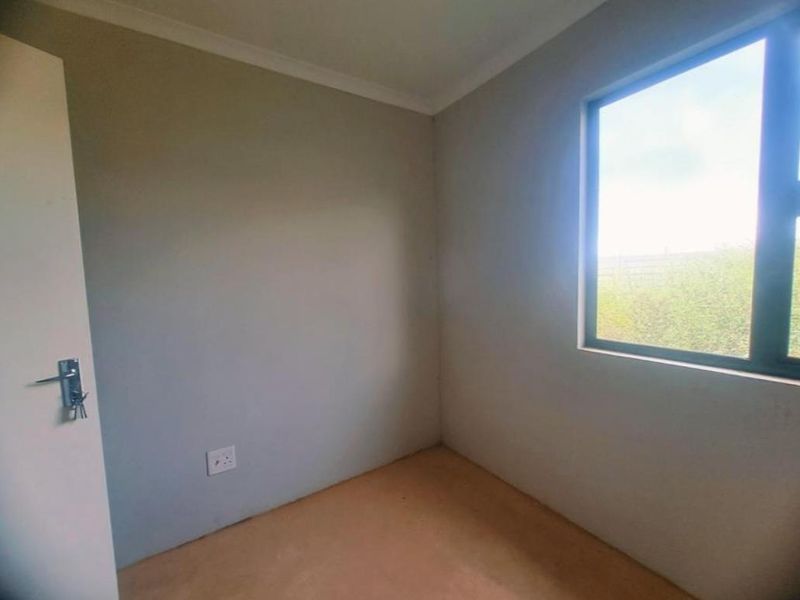 An empty bedroom featuring neutral walls, an aluminium window, and unfinished flooring, offering a blank canvas for custom interior design.