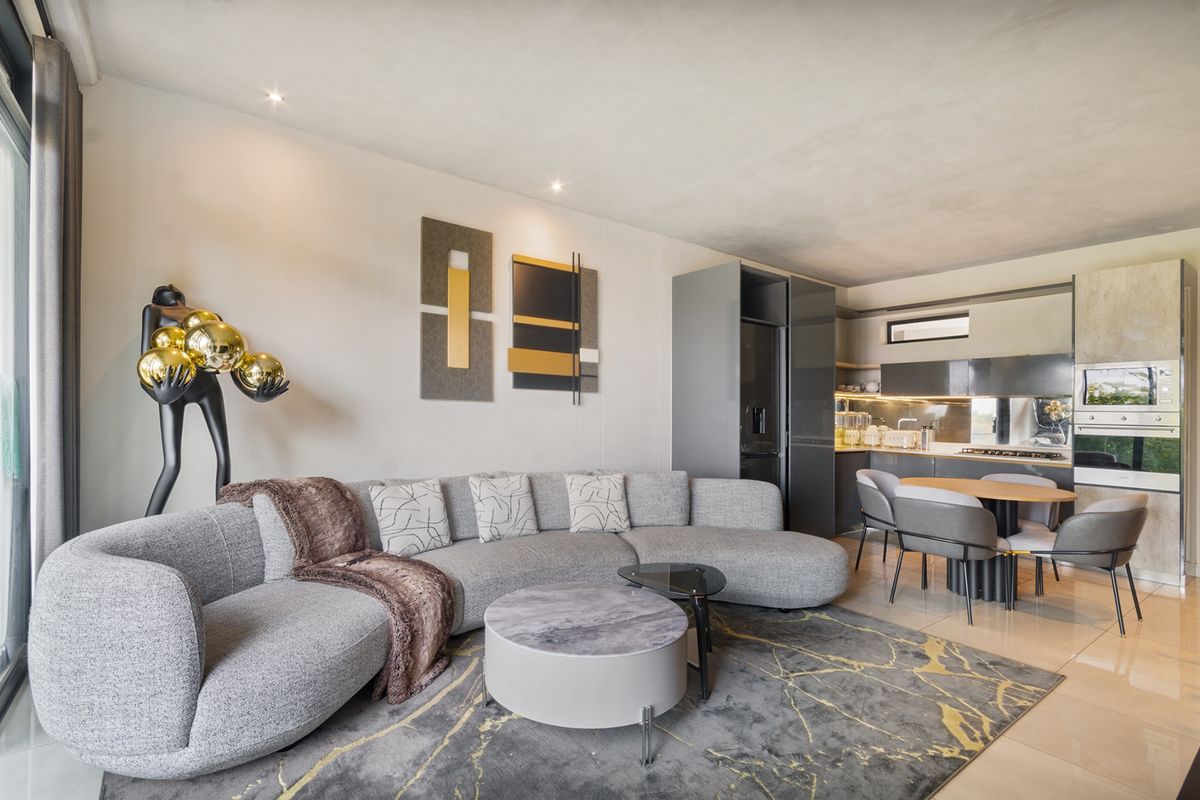 Modern open-plan living area featuring a sleek kitchen with integrated appliances, tiled floors, and recessed lighting, seamlessly flowing into the lounge space.