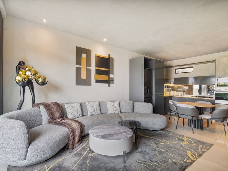 Modern open-plan living area featuring a sleek kitchen with integrated appliances, tiled floors, and recessed lighting, seamlessly flowing into the lounge space.