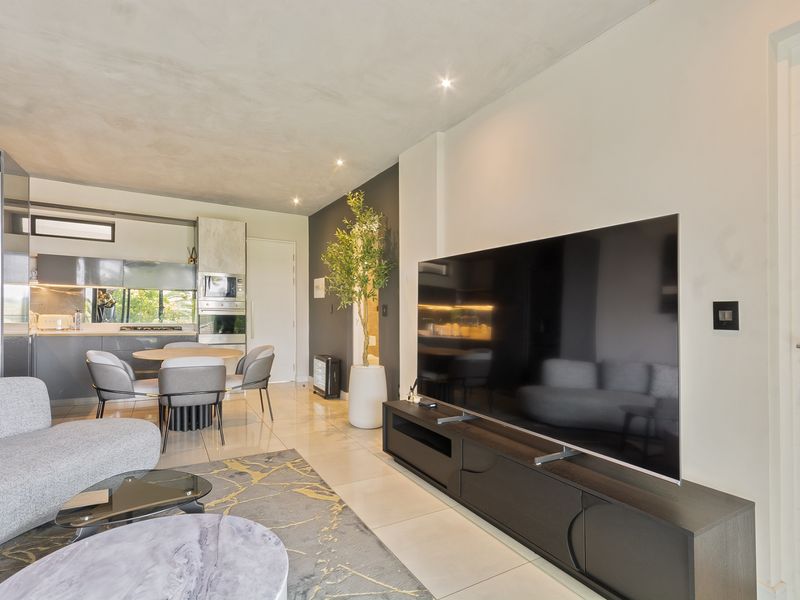 Modern open-plan living area featuring sleek cabinetry, integrated kitchen appliances, recessed lighting, and polished tiled flooring in a contemporary apartment setting.