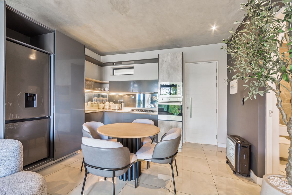 Modern open-plan kitchen featuring sleek grey cabinetry, integrated appliances, and high-quality tiled flooring in a contemporary apartment setting.