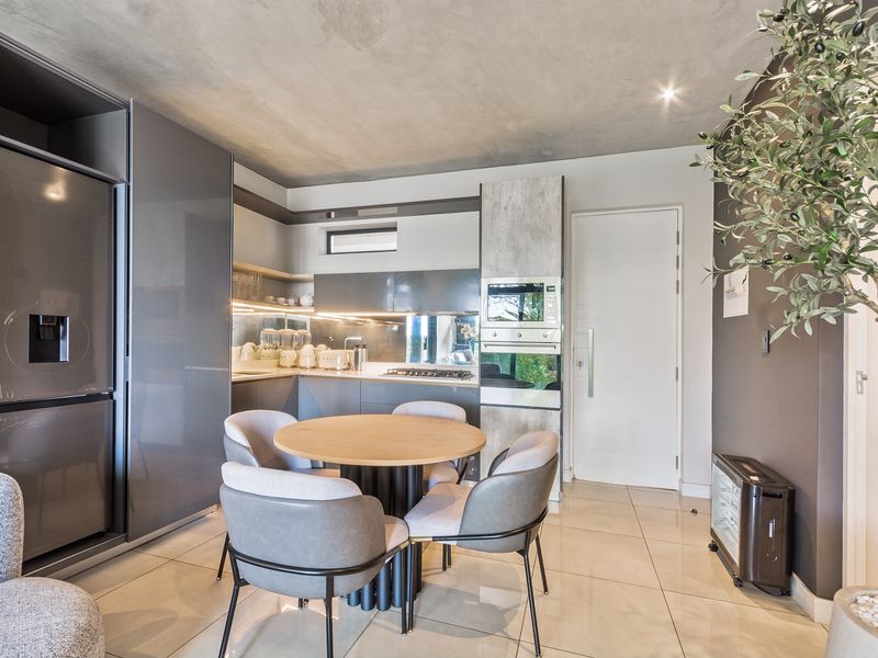 Modern open-plan kitchen featuring sleek grey cabinetry, integrated appliances, and high-quality tiled flooring in a contemporary apartment setting.